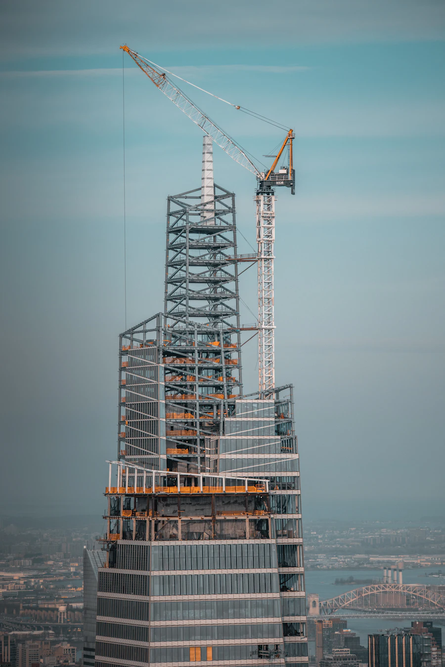 High-rise core rising under a tower crane above a city