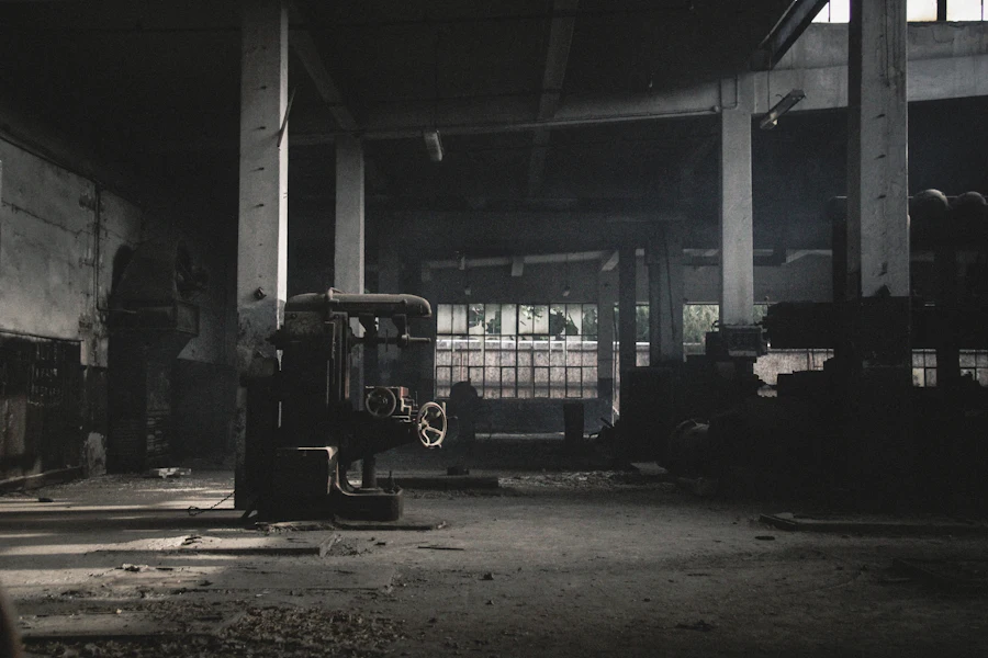 Dark industrial hall with heavy machinery and shafts of light