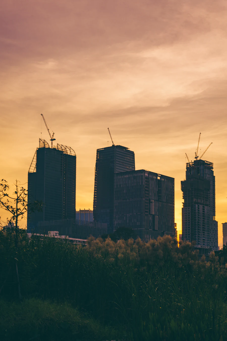 Silhouetted high-rise towers against an orange sunset sky