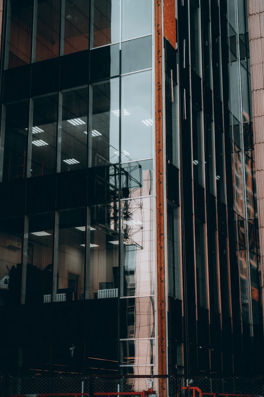 Dark glass office facade with a red steel edge in evening light